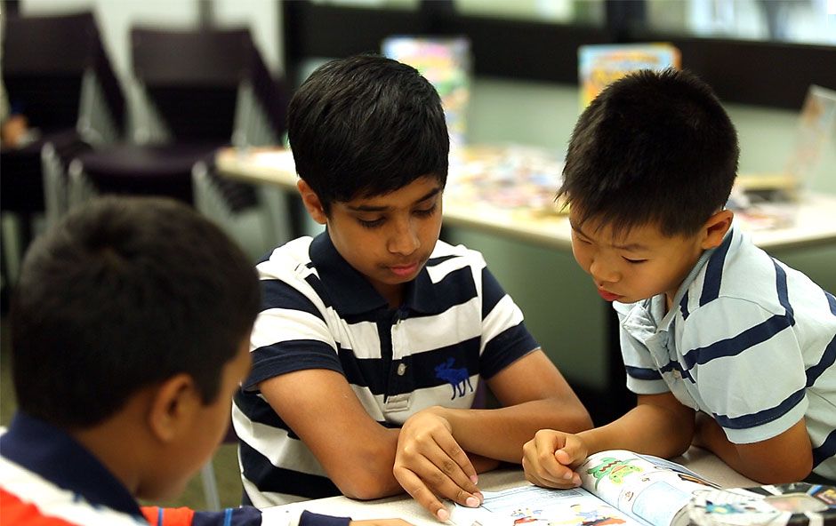 Trois enfants de nationalités différentes lisent des livres